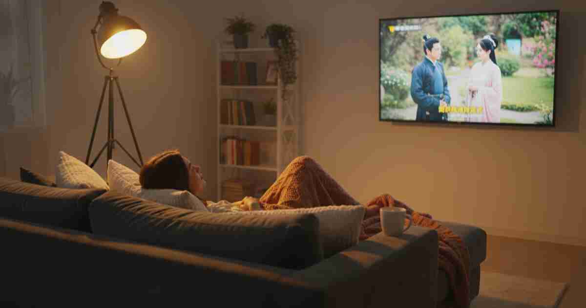 Person relaxing on couch watching a foreign language TV show with subtitles