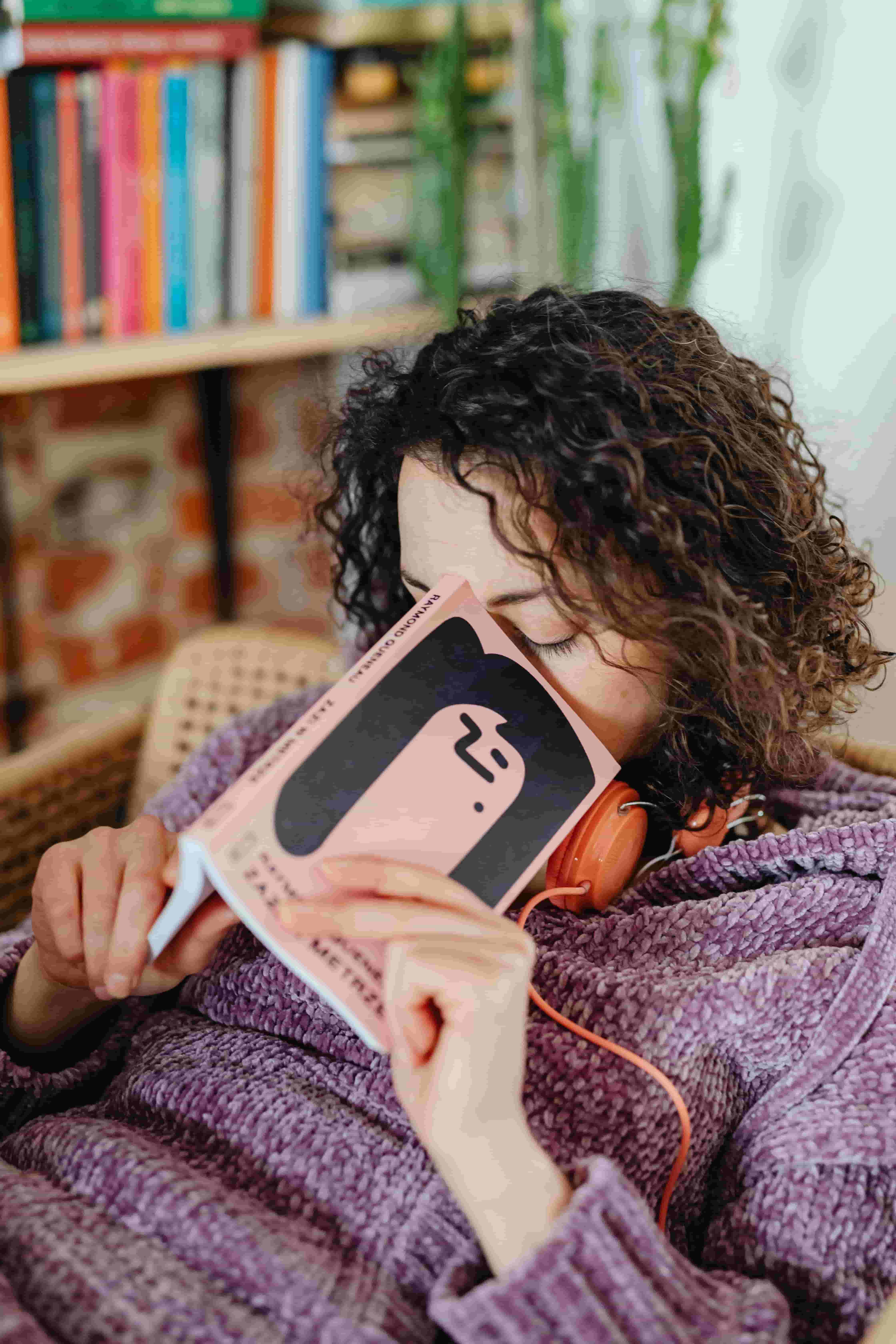 Person sleeping with headphones on next to a book about learning Spanish